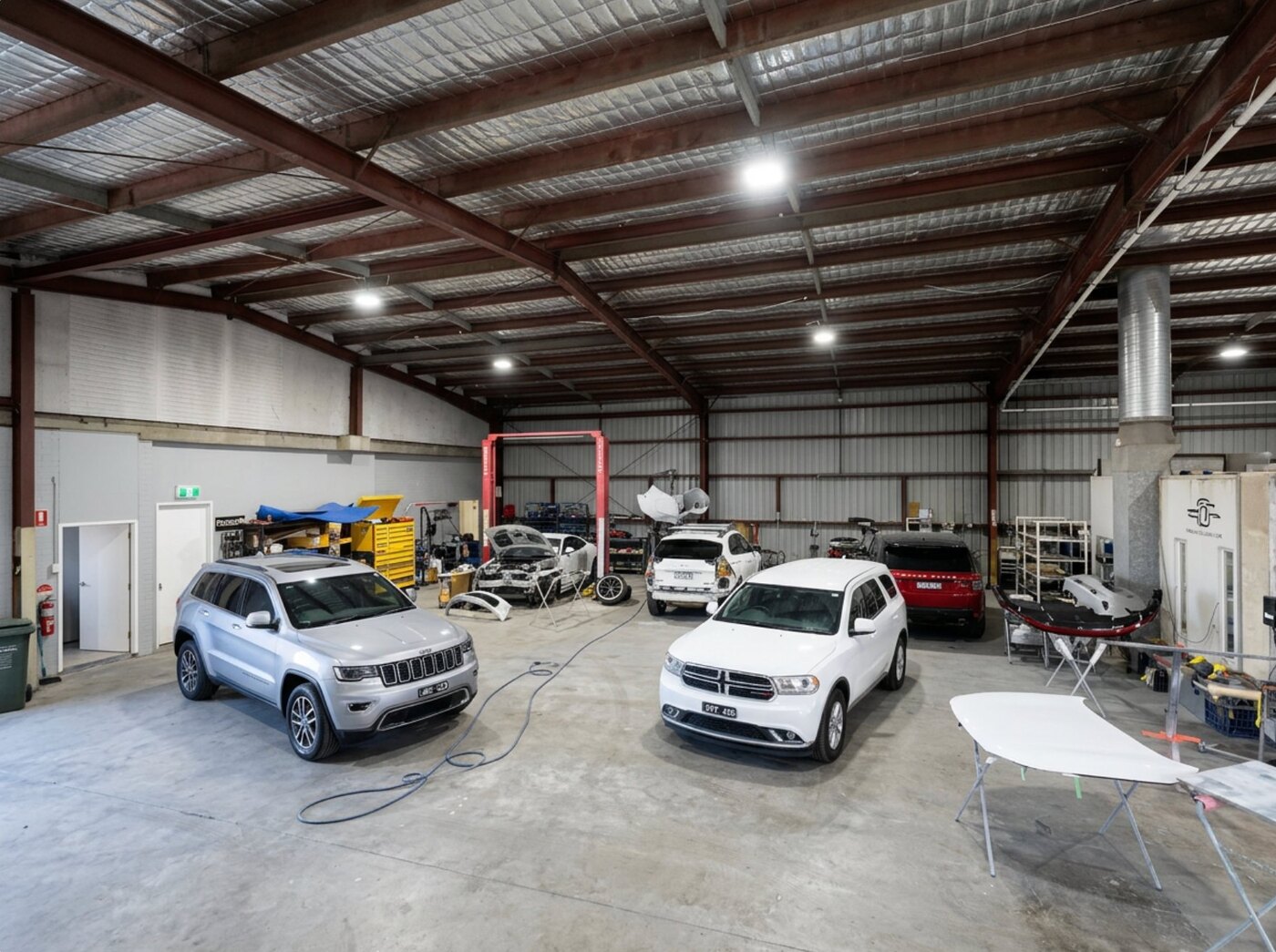 Vehicles being repaired inside the All Gosford Smash Repairs workshop in West Gosford